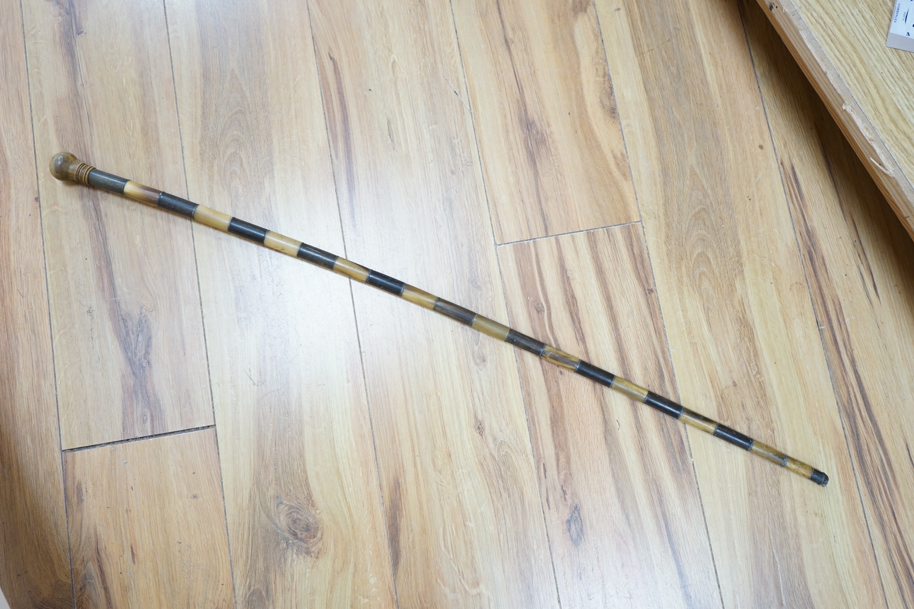 An African two colour banded horn walking stick with turned handle, 87cm in length. Condition - fair, bowed